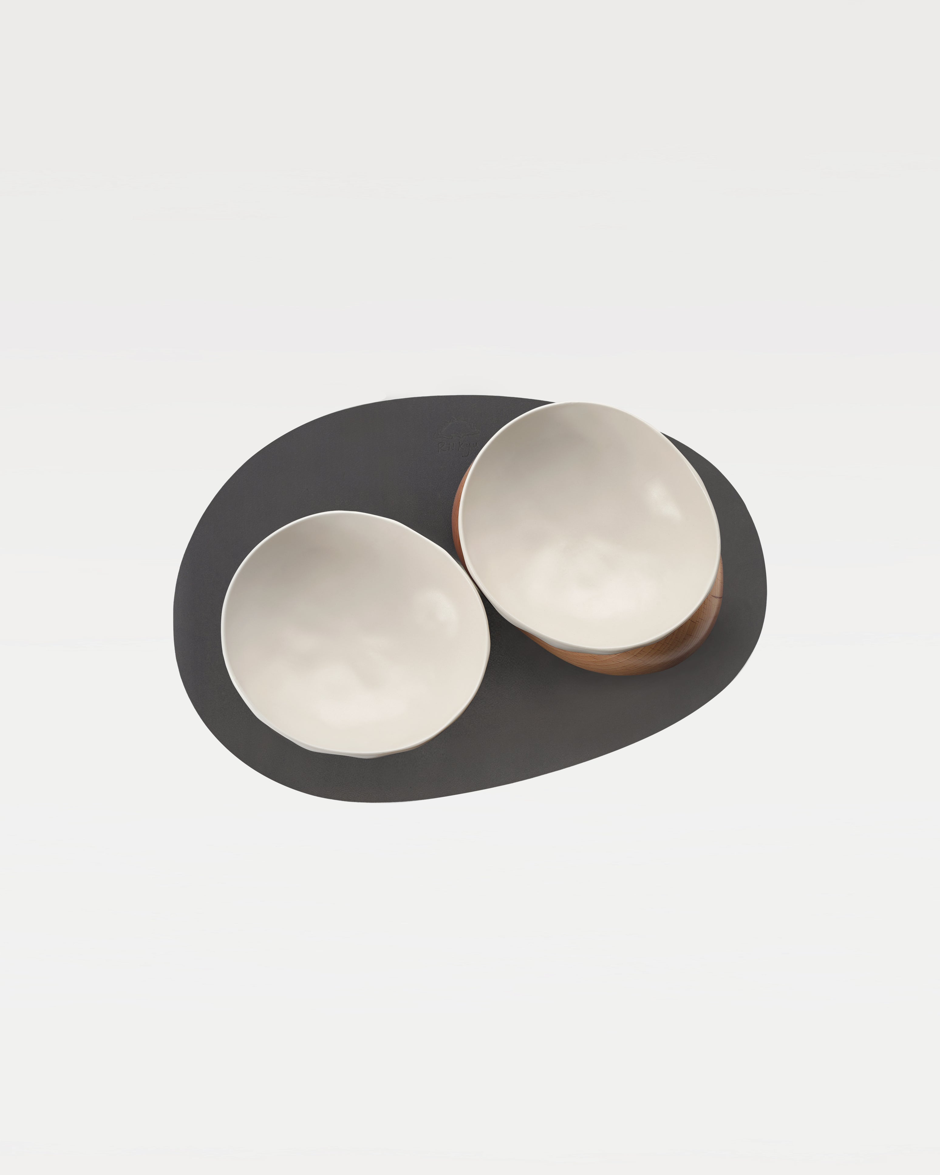 top view of two white bowl, two wooden bases and a black mat