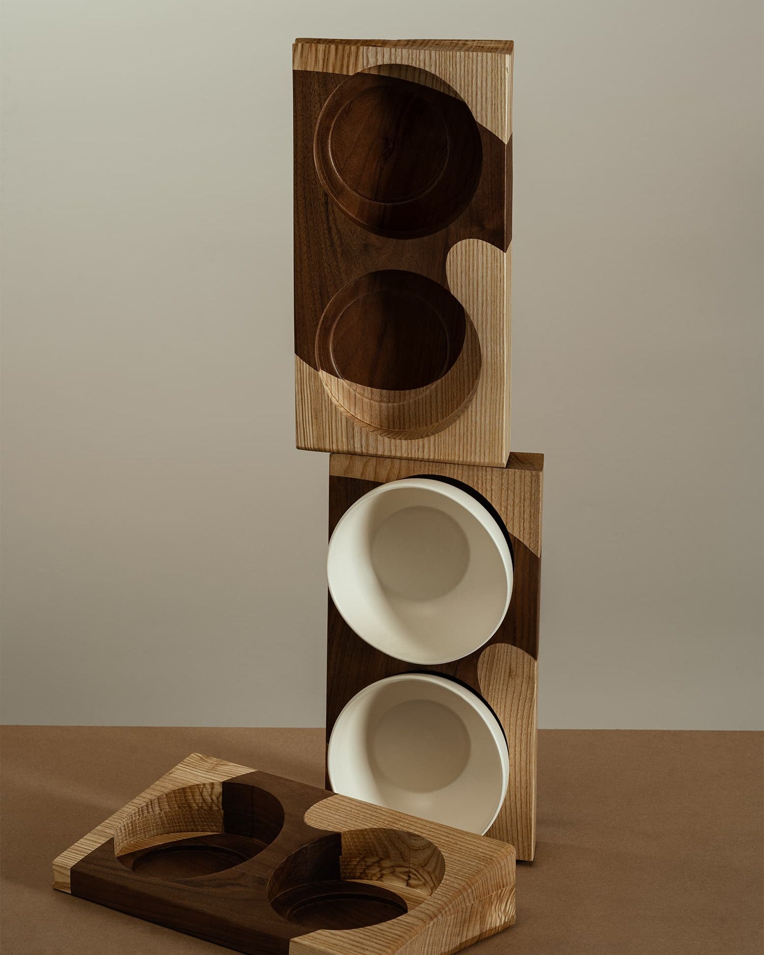 Three two-color wooden bases, with two white bowls placed on the middle base