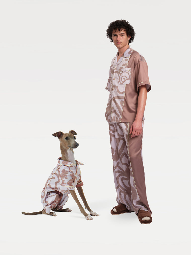 A male model stands with a dog sitting to his left, both wearing pajama sets.