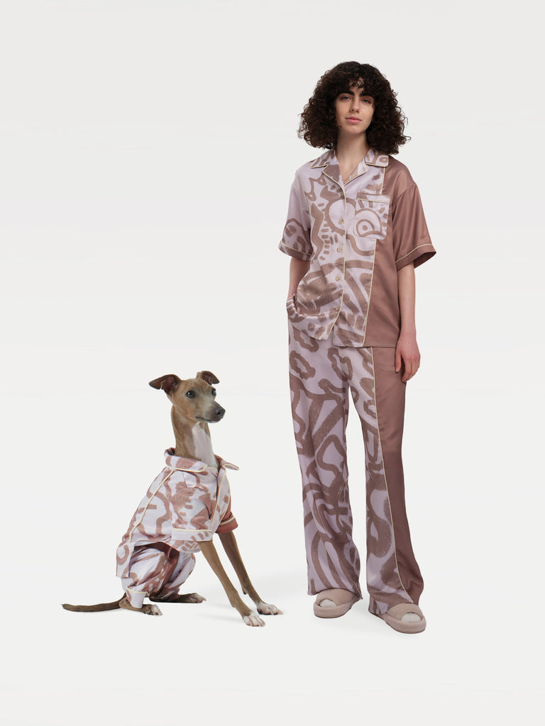 A female model stands with a dog sitting to her left, both wearing pajama sets.