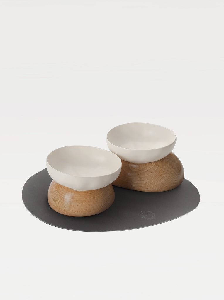 two white bowls, two wooden bases and a black mat