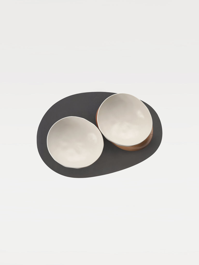 top view of two white bowl, two wooden bases and a black mat