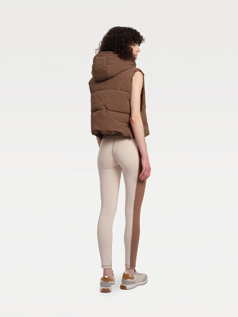 A female model standing back in a brown paded vest
