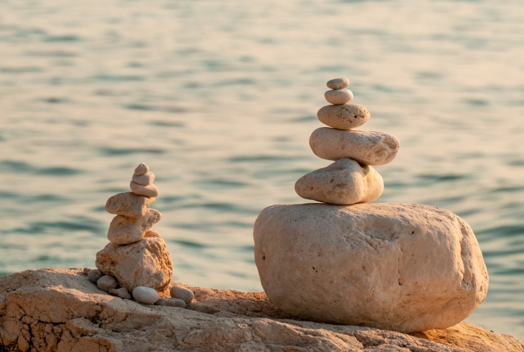 Several stones are stacked vertically into two groups in front of the sea